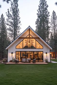 a large white house sitting on top of a lush green field next to tall trees