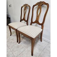 two wooden chairs sitting side by side in a room with tile flooring and white walls