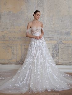 a woman standing in front of a wall wearing a wedding dress