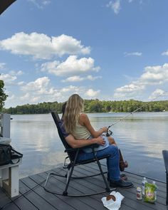 a woman sitting in a chair fishing on a lake