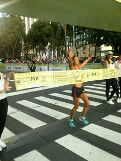 two women are running across the street holding a ribbon