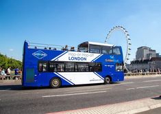 a double decker bus is driving down the street with people on it and ferris wheel in the background