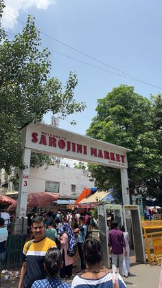 many people are walking around an outdoor market in the day time and there is a sign that says sahojuni market