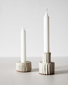 two white candles sitting on top of each other