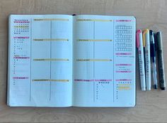 an open planner with three pens on it