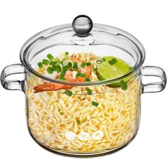 a large glass pot filled with noodles and vegetables next to a lime wedged slice