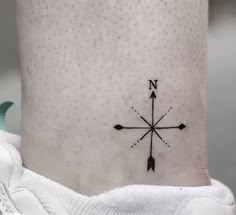 a small black and white compass tattoo on the side of a person's leg