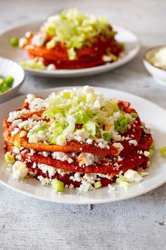 some food is on a white plate with sauce and green onions next to it, along with other dishes