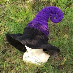 a purple and black knitted hat sitting on top of a white mannequin head