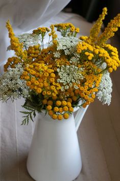 a white vase filled with yellow and white flowers