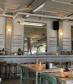 an empty restaurant with tables and chairs in front of the bar, filled with wine glasses