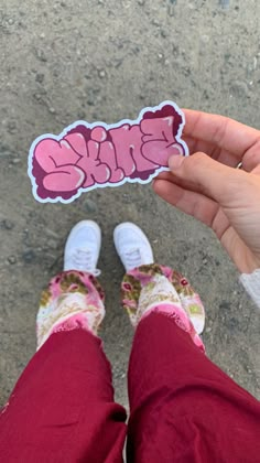 a person holding up a pink sticker with the word blkk on it