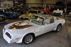 a white sports car parked in a garage next to other cars