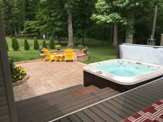 a hot tub sitting on top of a wooden deck next to a picnic table and yellow chairs