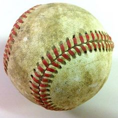 an old baseball with red stitchs is on a white surface and it appears to be in motion