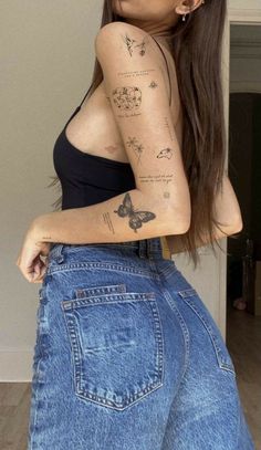 a woman with tattoos on her arm and leg, posing for the camera in jeans