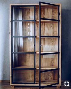 a wooden bookcase with glass doors on the front and bottom shelves, against a gray wall