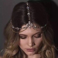 a woman wearing a tiara and looking down at her face, with long wavy hair