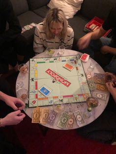 a group of people sitting around a table with a monopoly board game on top of it