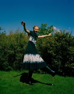 a woman in a black and white dress is posing for the camera with her arms outstretched