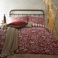 a bed with red and white bedspread in a bedroom next to a christmas tree