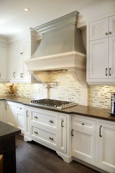 a large kitchen with white cabinets and black counter tops on the island in front of the stove