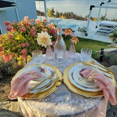 the table is set with pink and gold place settings for two people to sit at