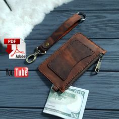 a leather wallet with a keychain attached to it on a wooden table next to an id card holder