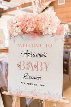 a welcome sign for a baby shower is hanging on a easel at the reception