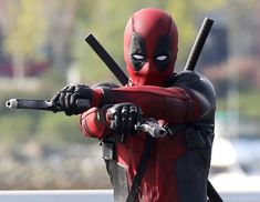 a deadpool is holding two swords in his hands