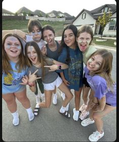 a group of young women standing next to each other in front of a house with their hands up