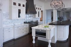 a large kitchen with white cabinets and black counter tops, an island that has apples on it