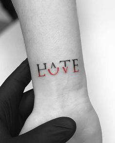 a person's wrist with the word love tattooed on it, in red ink