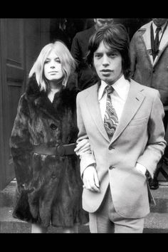 a man in a suit and tie standing next to a woman wearing a fur coat