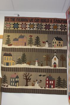 a quilt hanging on the wall with snowmen and houses in it's borders