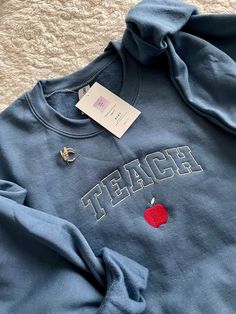 "The softest and coziest crewneck to hold you down this school year! Represent teacher life whether you're a teacher yourself or know a great teacher - this sweatshirt is perfect especially when personalized with their name!  Standard thread colors will come as seen in primary listing photos (creme yellow), if you'd like to change the thread colors, please list in the personalization box.  *Please note: if you like the pink option as seen in listing photo on gray sweatshirt, just list \"PINK OPT Crikit Ideas, Teacher Appropriate Outfits, Teach Sweatshirt, Cute Teacher Outfits, Teacher Accessories, Teacher Aesthetic, Teacher Vibes