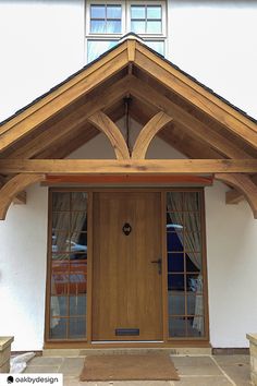 the front door of a white house with wood trimmings and arched window frames