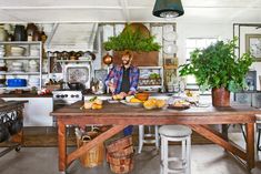 a man standing in a kitchen preparing food on top of a wooden table next to a potted plant