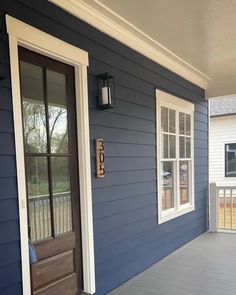 the front porch is painted blue with white trim and wood door, along with two windows