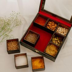 an open wooden box filled with different types of spices and nuts next to some dried flowers