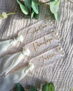 three wedding garters with names on them and some leaves around them, sitting on a table