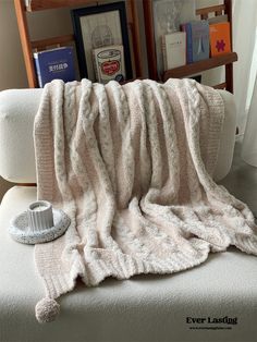 a white couch with a blanket on top of it next to a book shelf and bookshelf