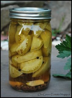 a jar filled with pickles sitting on top of a table next to a plant