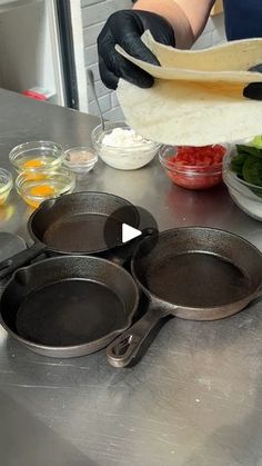 a person preparing food on top of a metal counter next to pots and pans