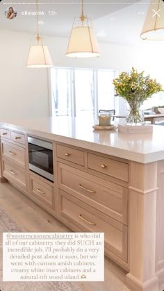 a large kitchen with an island in the middle and three lights hanging from the ceiling