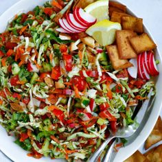 a white bowl filled with salad next to crackers and apple slices on a table