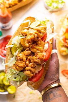 a person holding up a sandwich with chicken and lettuce