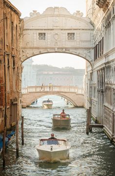 a boat traveling down a canal under a bridge in venice, italy stock - fotor