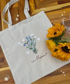 sunflowers and a tote bag with the word welcome on it sitting on a wooden floor