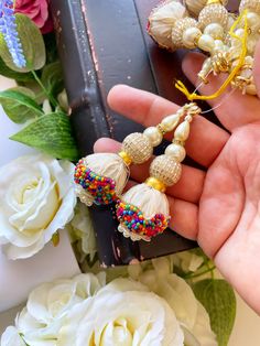 a person is holding some beads in their hand next to flowers and other things on the table